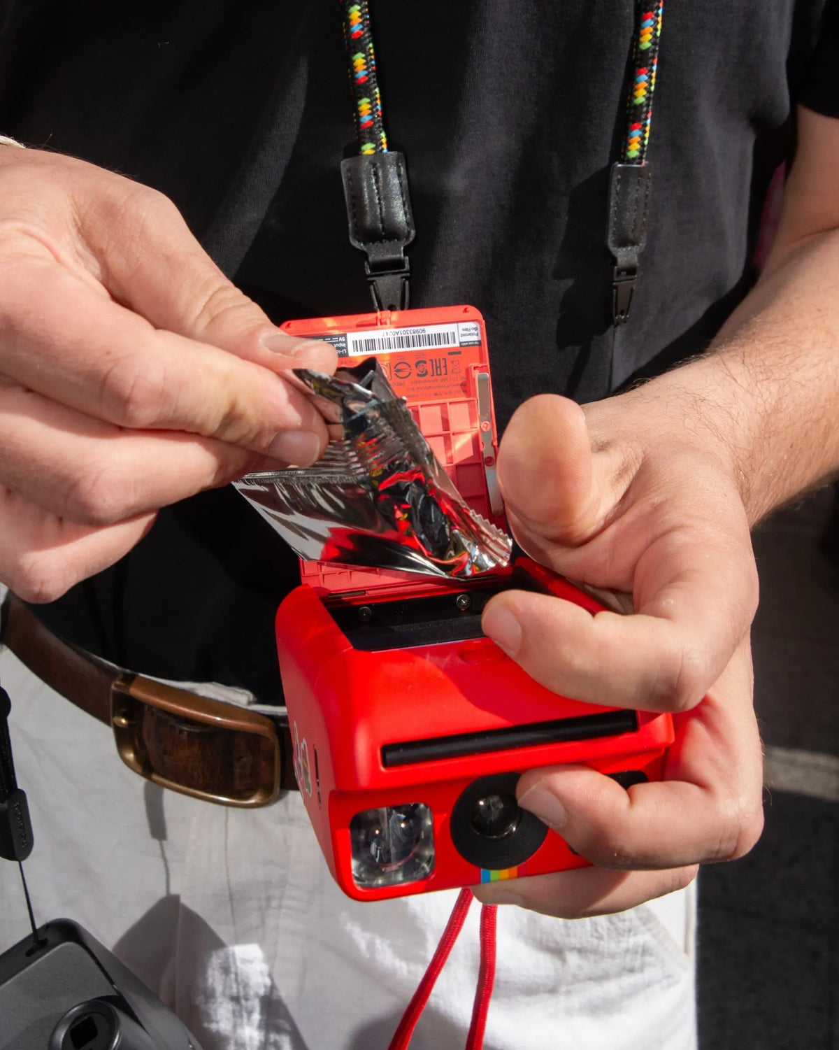 Instant film pack being inserted into a red camera