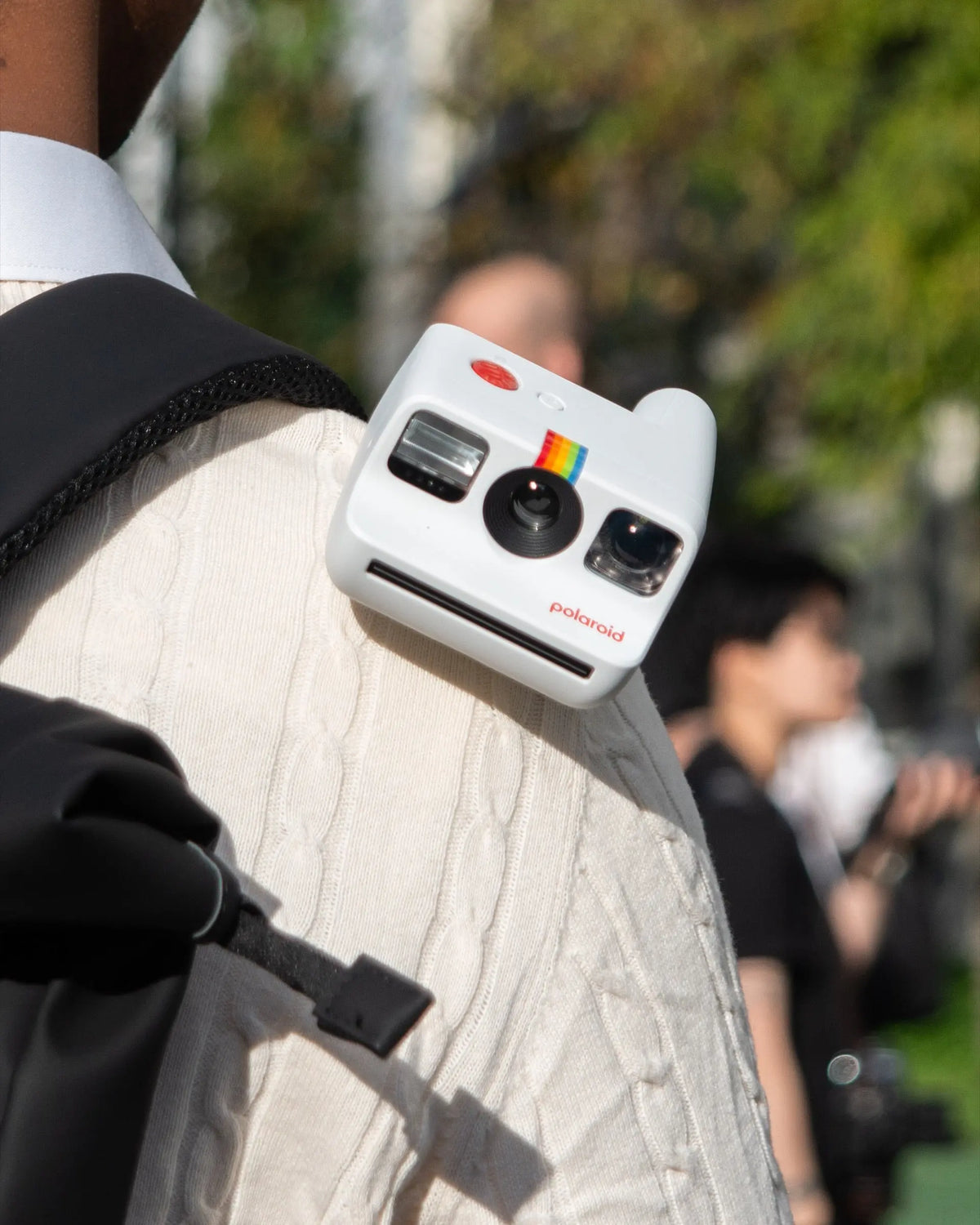 White instant camera attached to a bag in sunlight