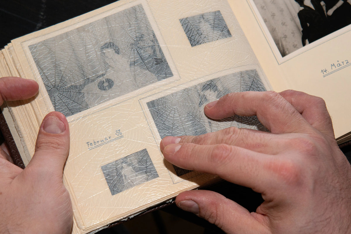 Hands carefully organising old family negatives in protective album sleeves