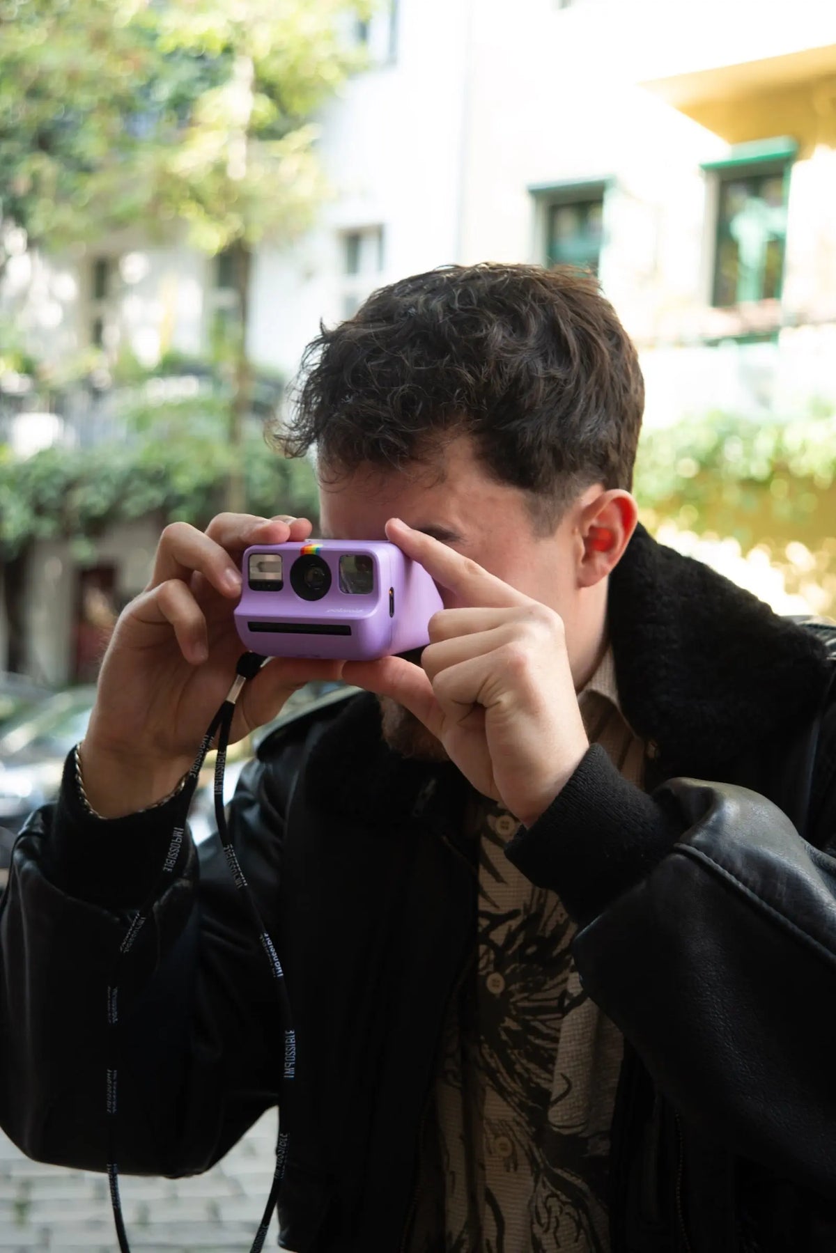 Photographer using a purple instant camera outdoors